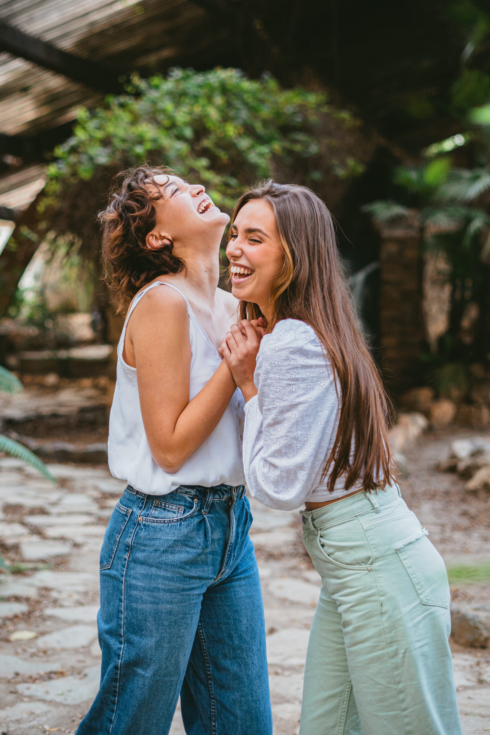 Two young teenager girl friends laughing surrounded by plants